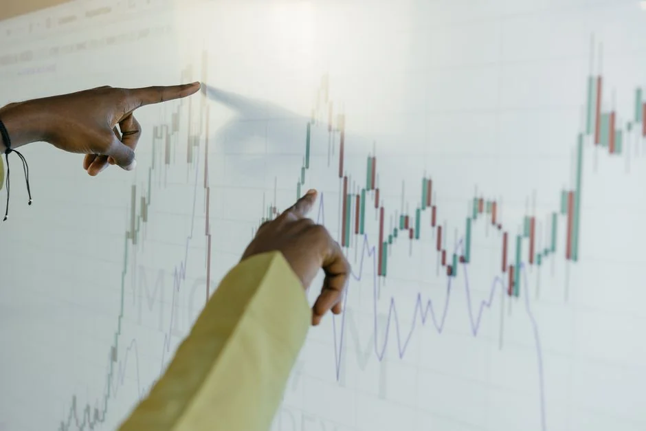 Hands using smartphone trading app with charts, dollar bills in background.